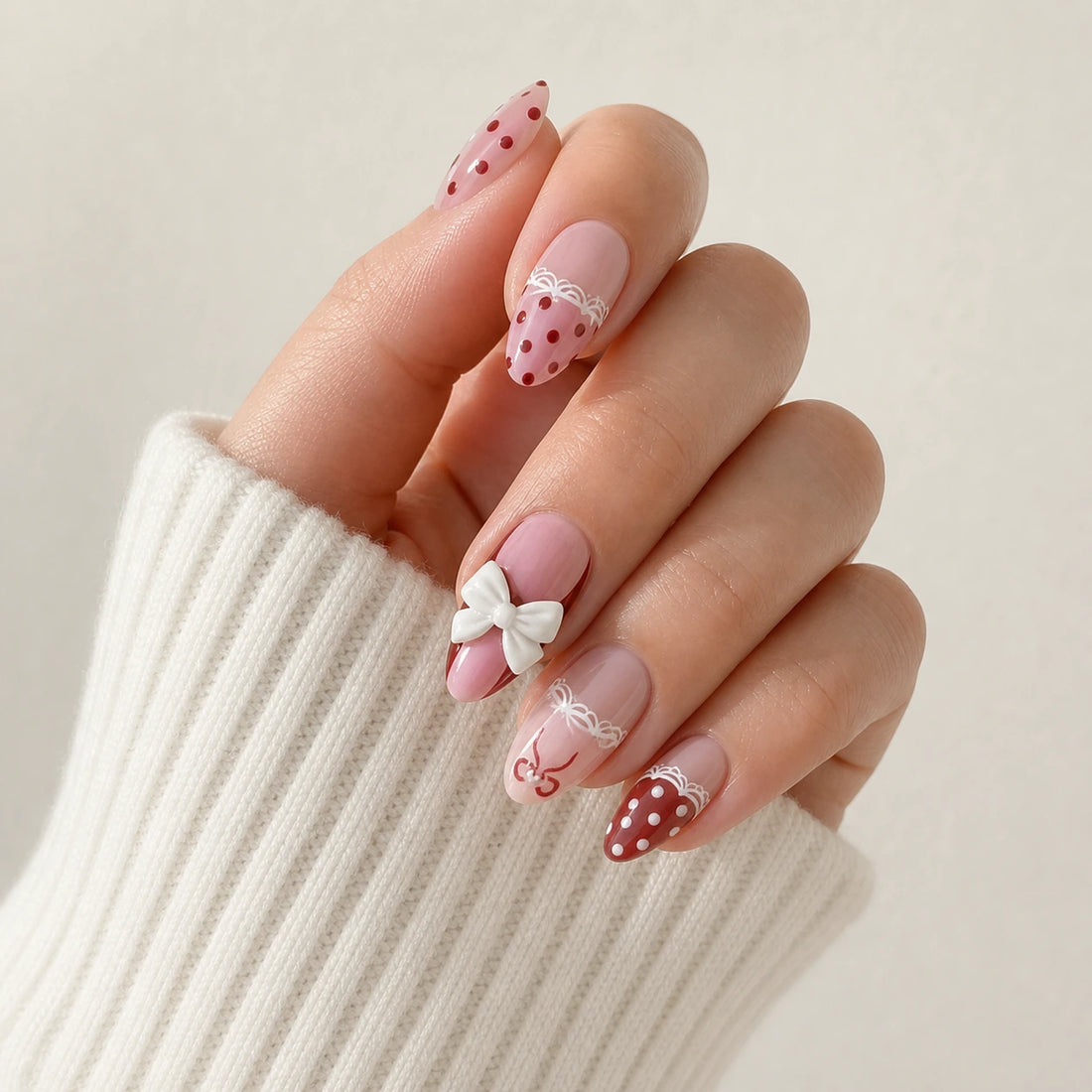 Polka Pirouette pink bow medium almond press-on nails on one softly curled hand, previous version