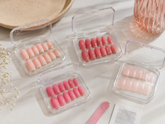 Soft and bright pink press-on nails arranged in clear plastic cases with a nail file and prep pad