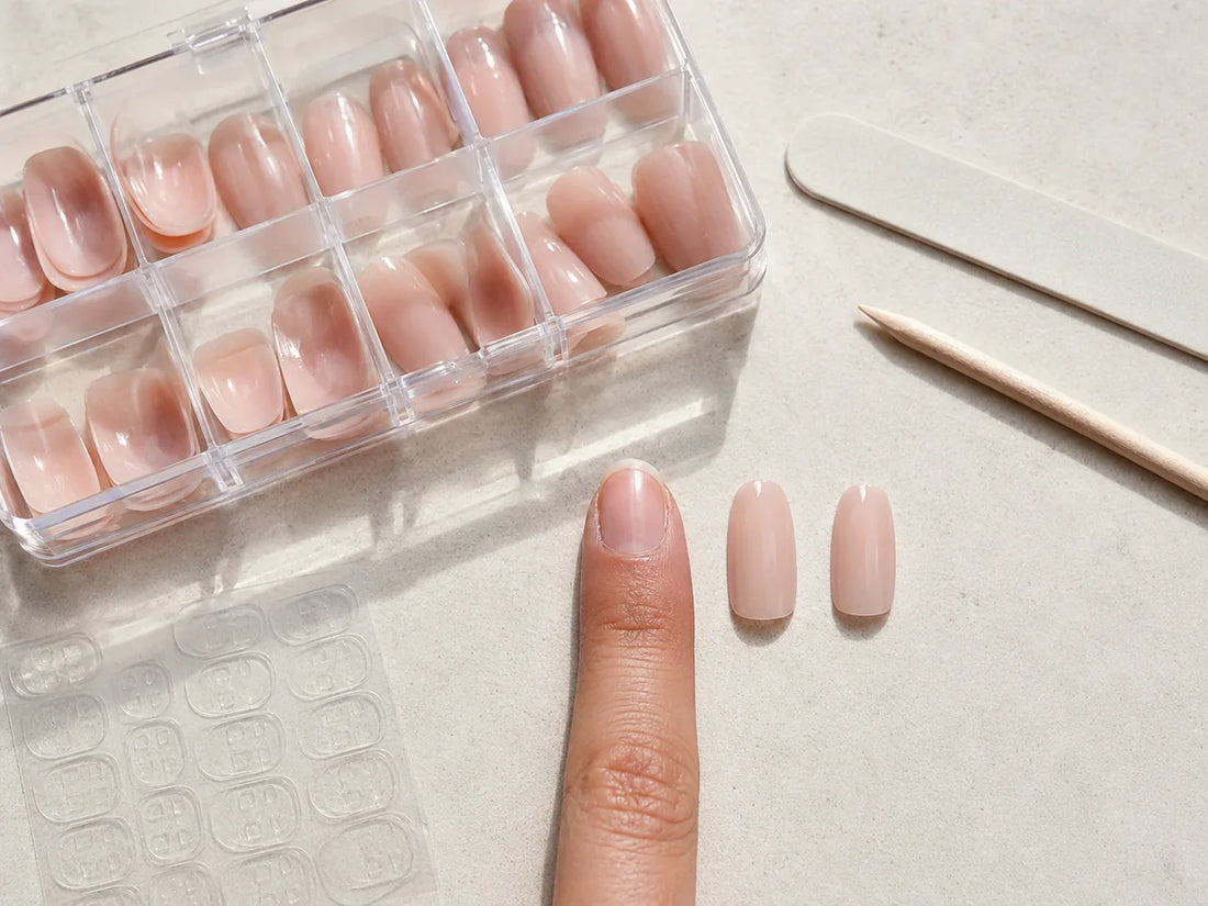 Choosing press-on nail sizes from a clear plastic nail case before applying