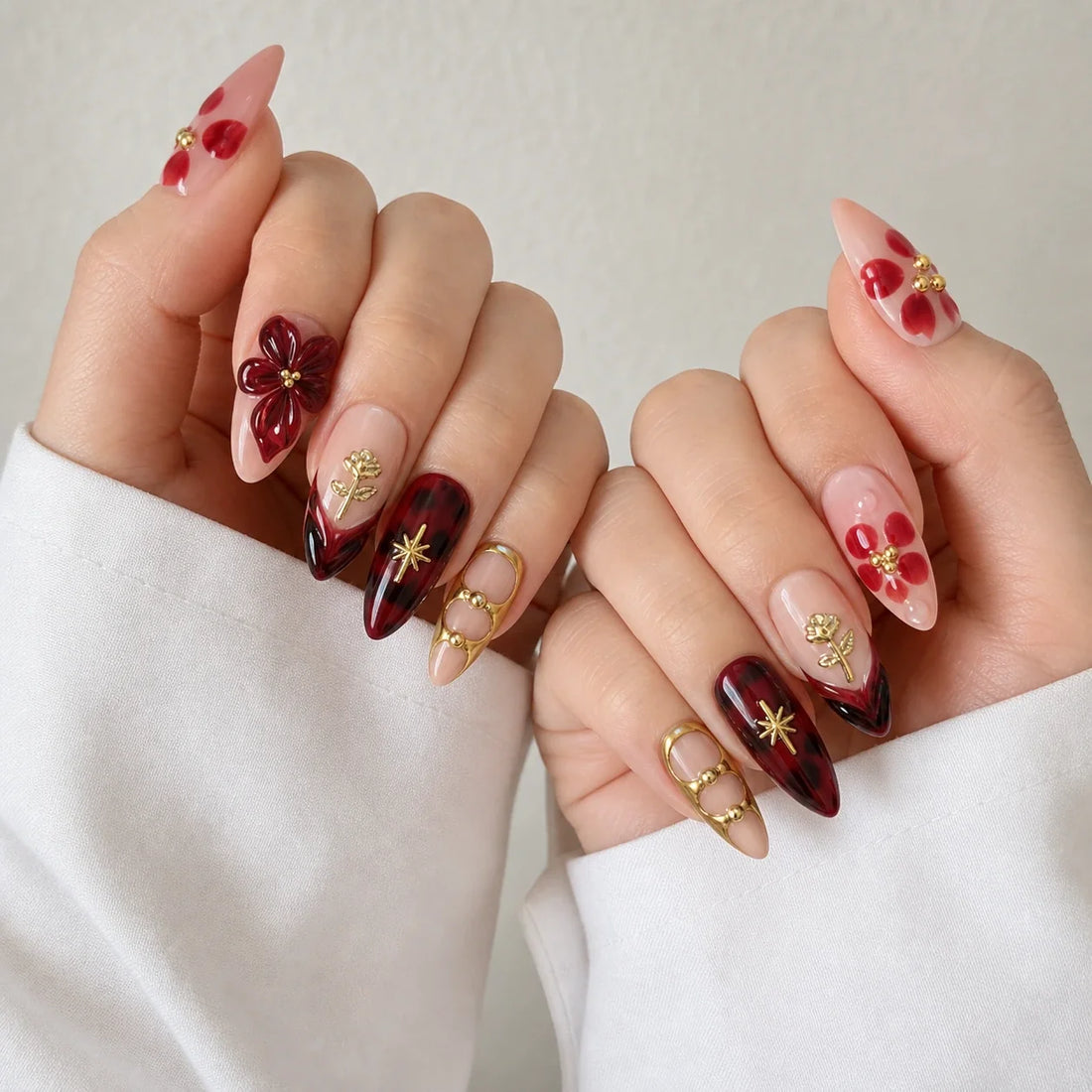 Crimson Keepsake romantic burgundy manicure on two softly curled hands