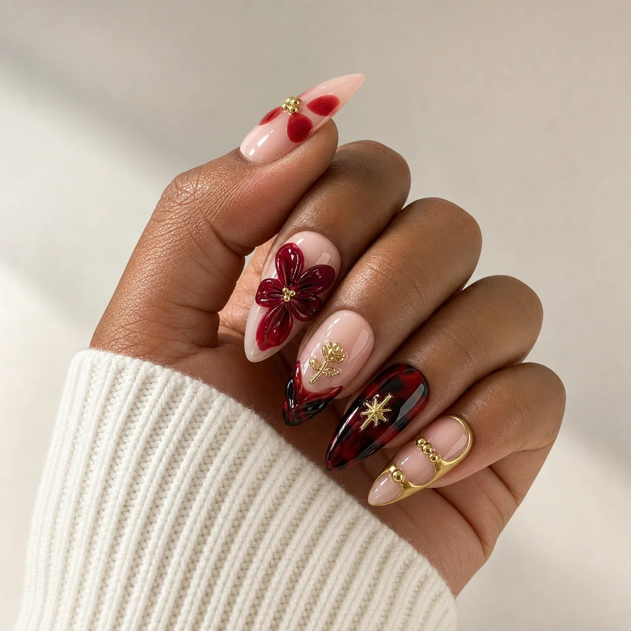 Crimson Keepsake gold floral manicure on one medium-brown hand