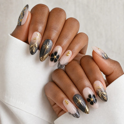 Astral Petal black and gold manicure on two medium-brown hands