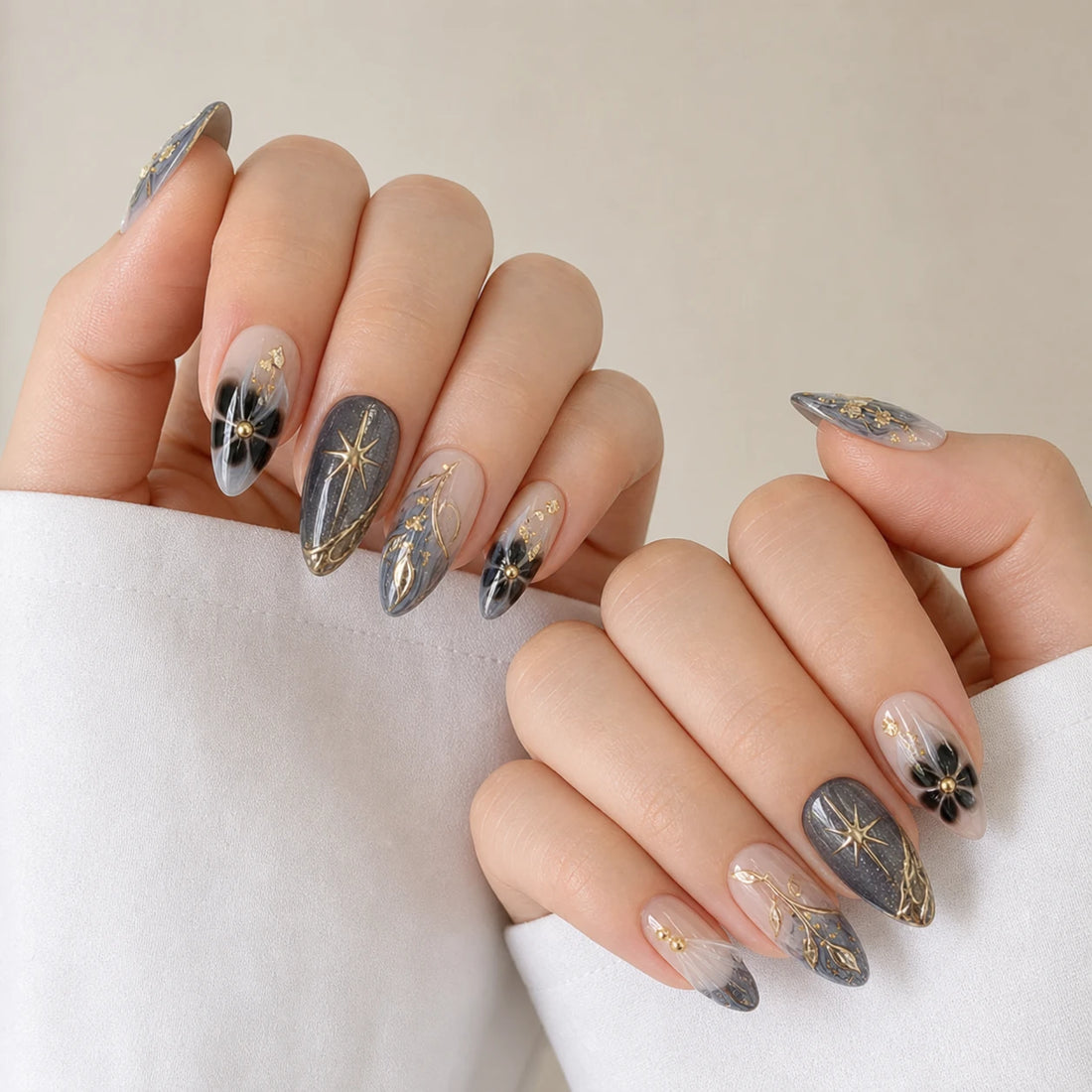 Astral Petal celestial botanical medium almond manicure on two softly curled light-skinned hands