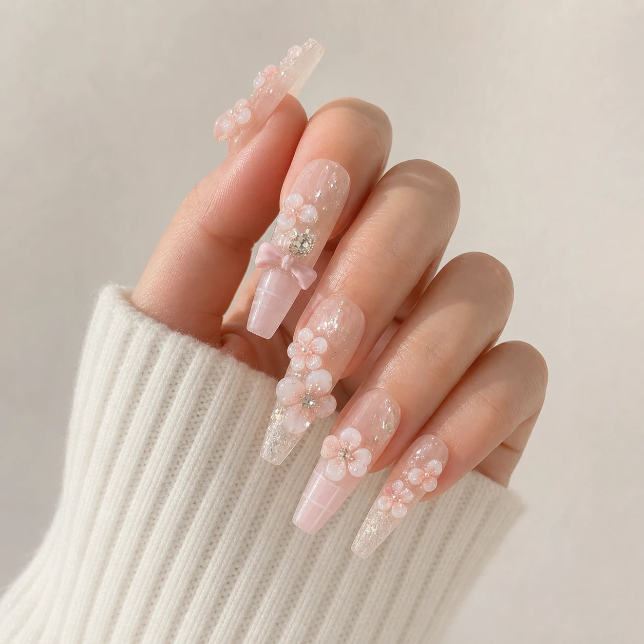 Blossom Sonata flower and bow manicure on one curled light-skinned hand