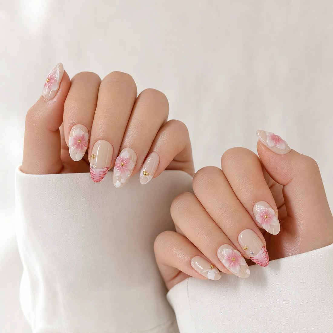 Blush Floralia medium almond floral press-on nails on two softly curled hands