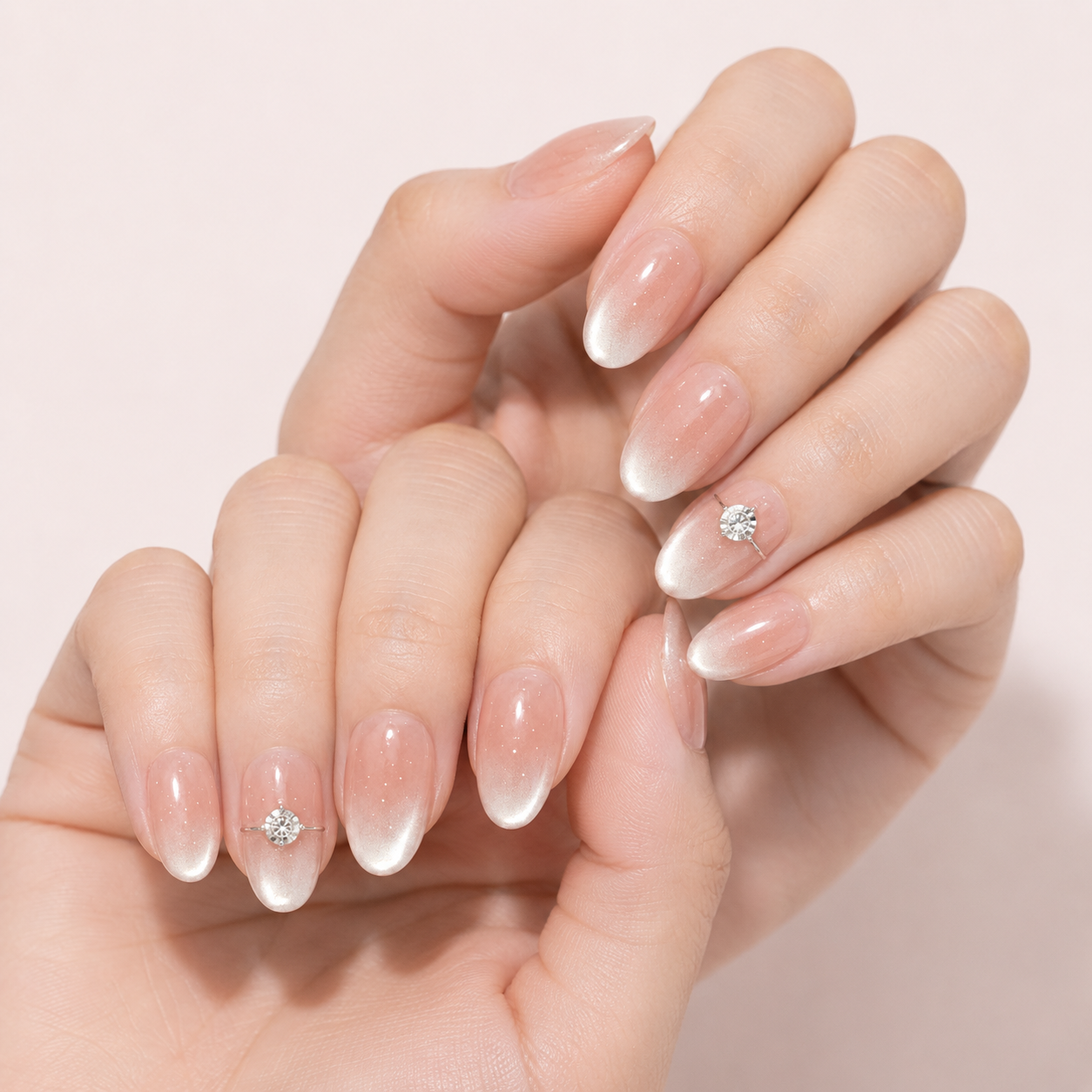 Close view of two light-skin hands wearing Blush Solitaire press-on nails with crystal accents