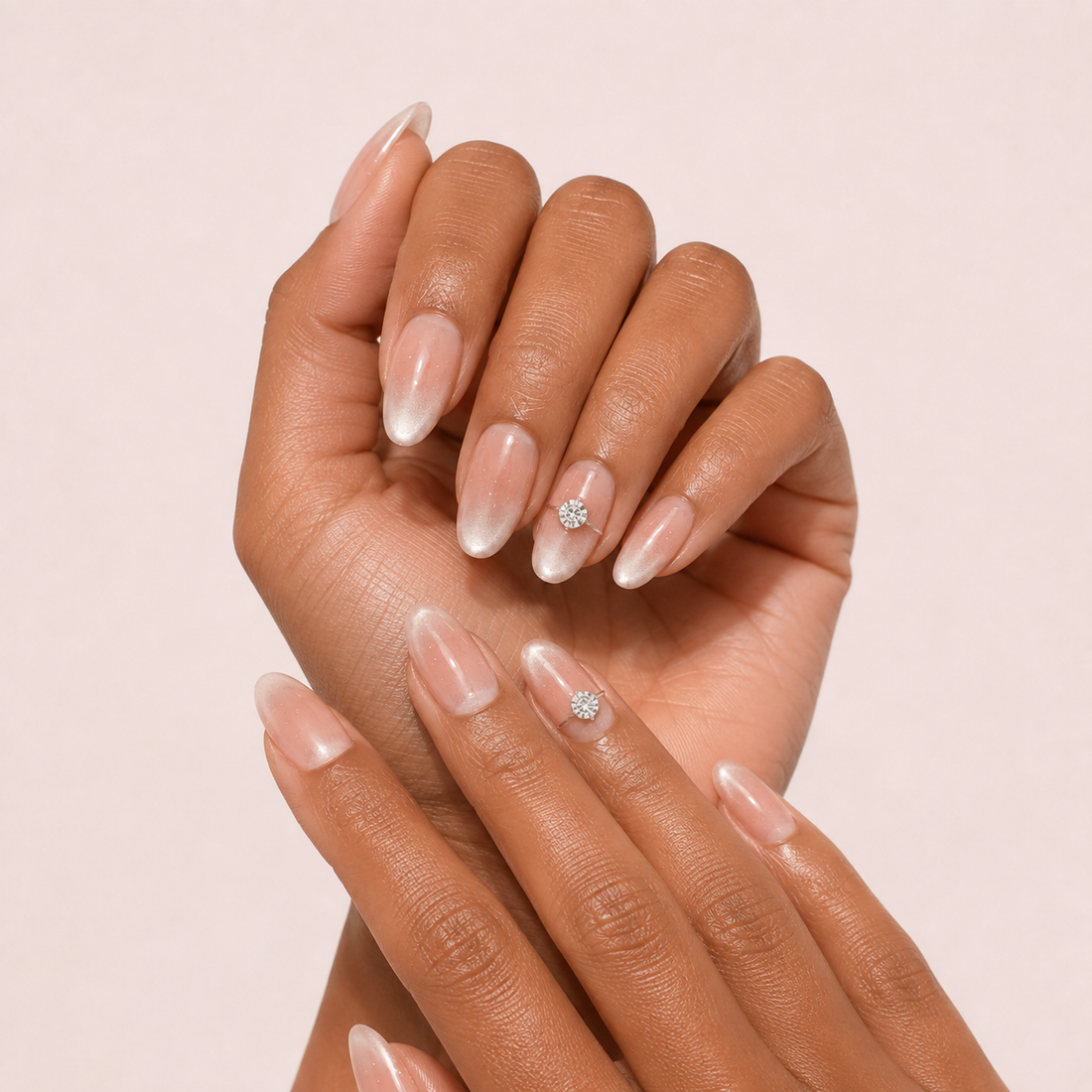 Two medium-brown hands wearing Blush Solitaire Medium Oval blush cat-eye press-on nails