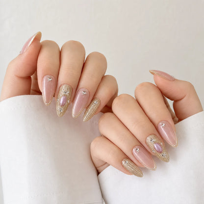 Champagne Oracle pink and gold cabochon manicure on two softly curled light-skinned hands