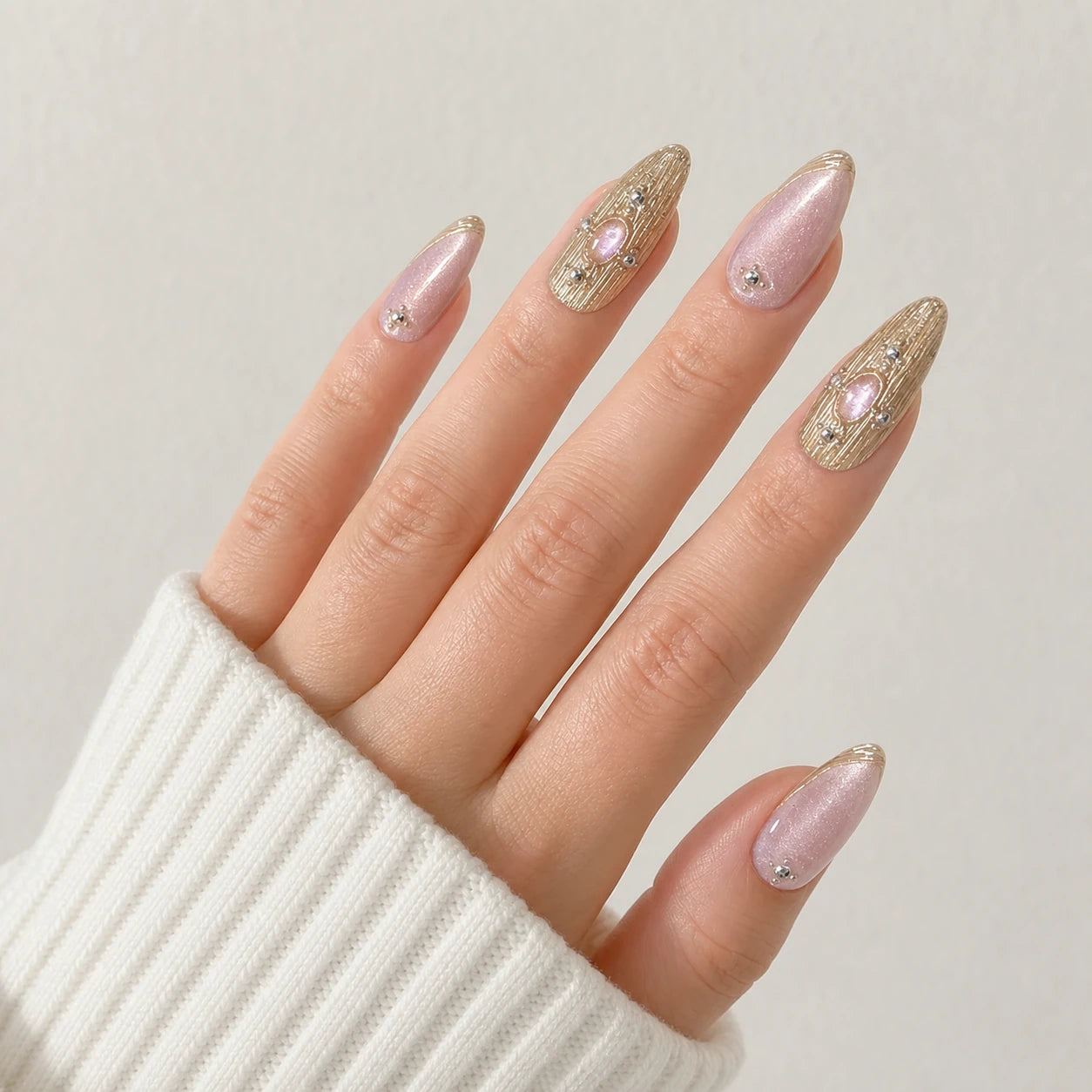 Champagne Oracle pink and champagne gold nails on one open light-skinned hand