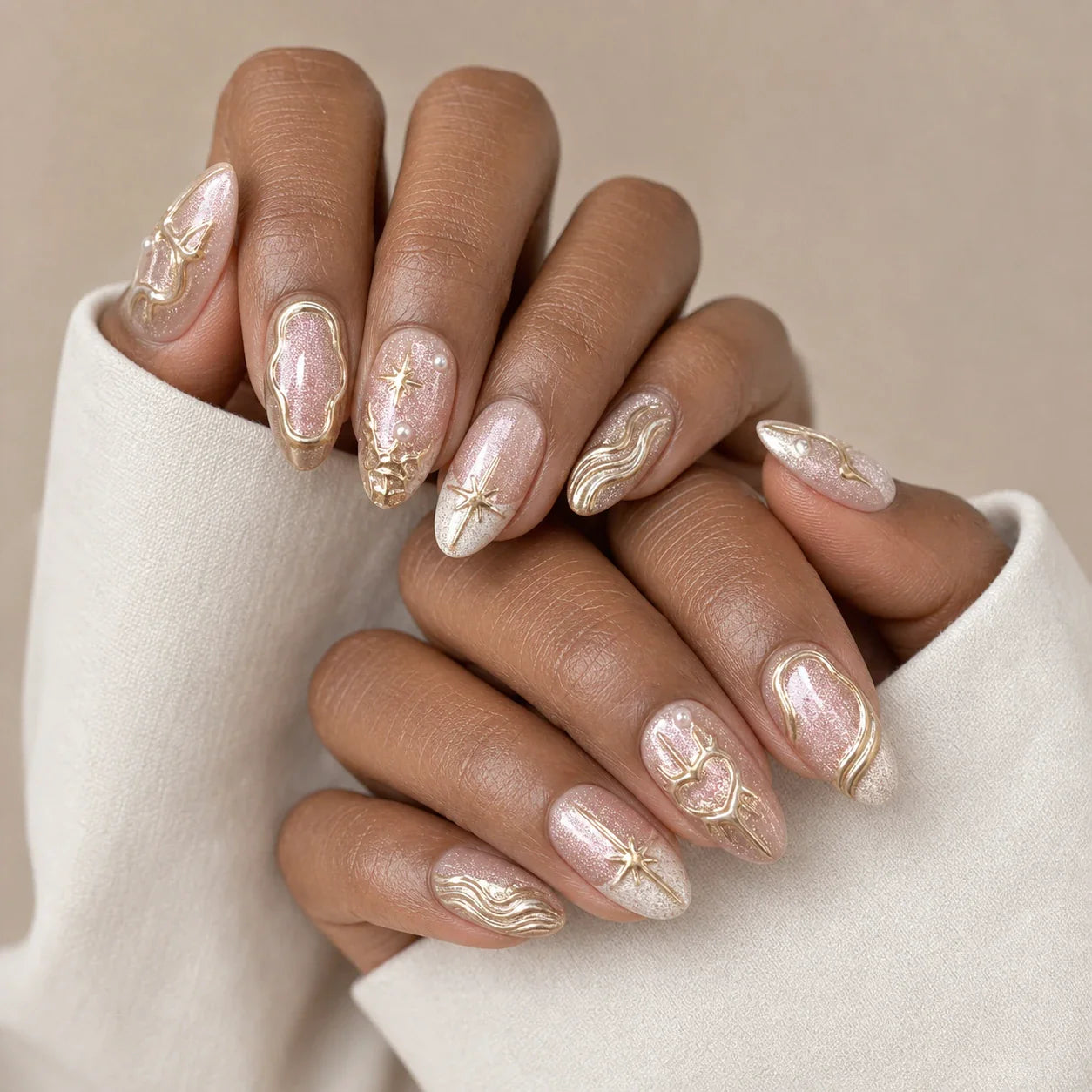 Champagne Zodiac metallic press-on nails on two medium-brown hands