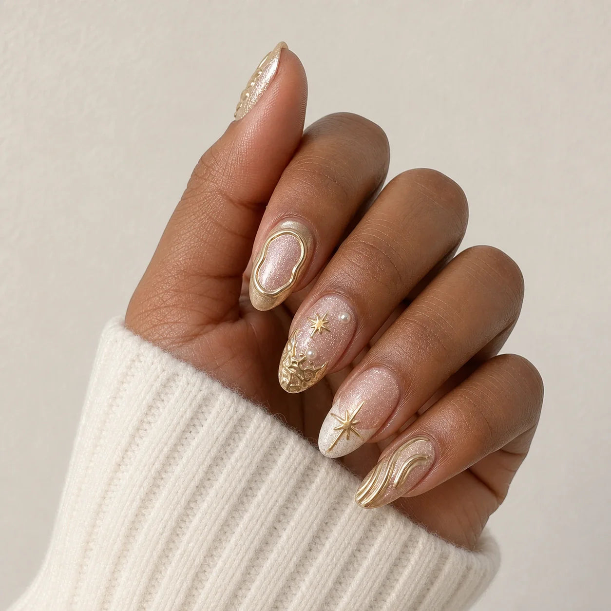 Champagne Zodiac celestial false nails on one medium-brown hand