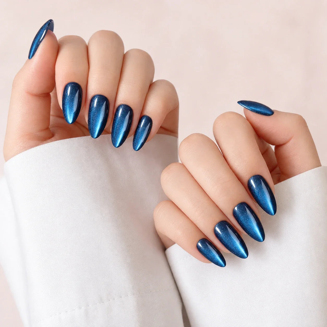 Cobalt Comet blue cat-eye medium almond press-on nails on two softly curled hands