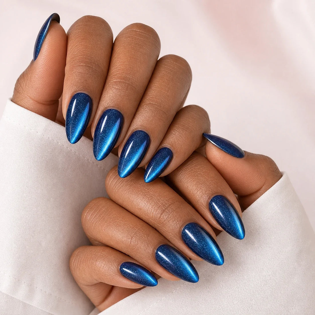 Cobalt Comet blue cat-eye medium almond press-on nails on two medium-brown hands