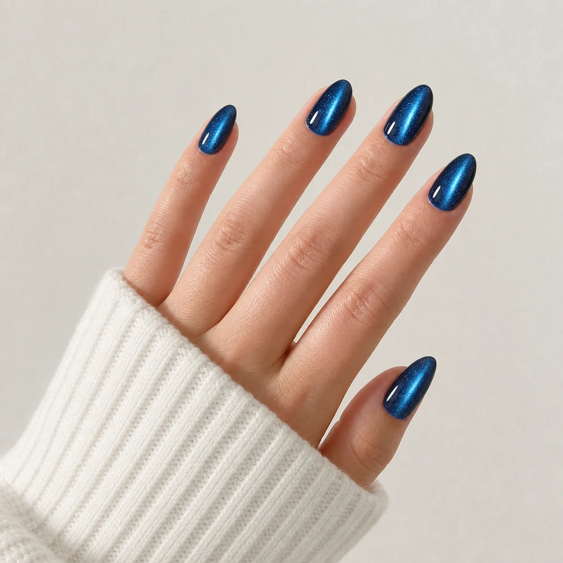 Cobalt Comet blue cat-eye medium almond press-on nails on one open hand