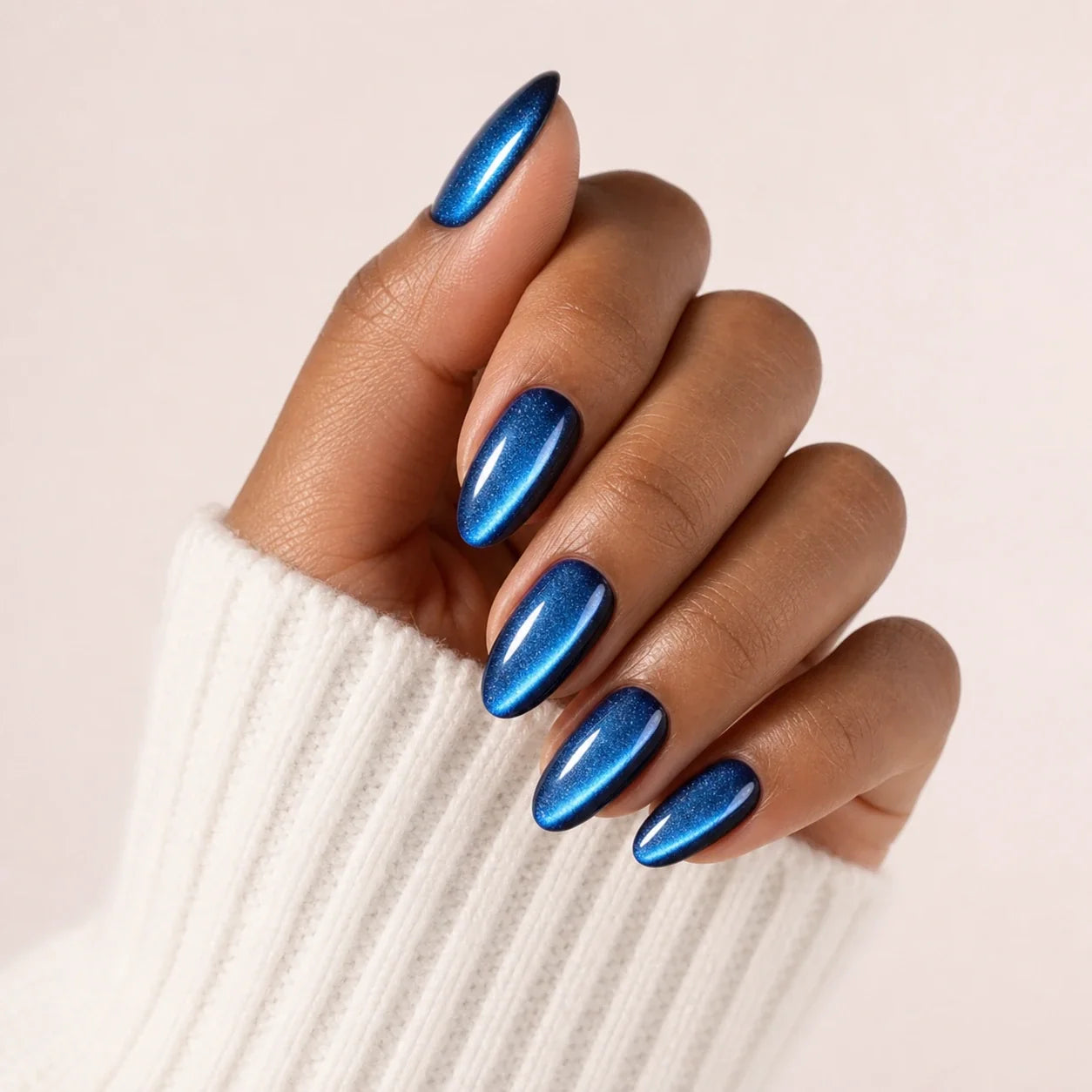 Cobalt Comet blue cat-eye medium almond press-on nails on one medium-brown hand