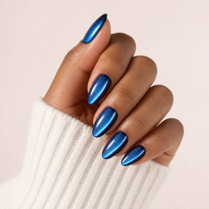 Cobalt Comet blue cat-eye medium almond press-on nails on one medium-brown hand