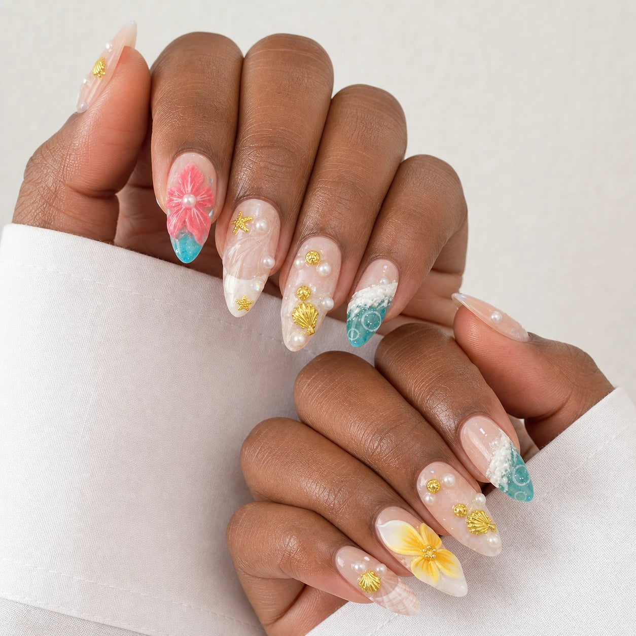 Coral Cabana shell and flower manicure on two medium-brown hands