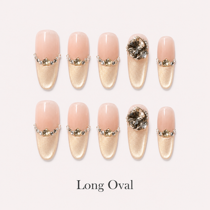 Gilded Cadence Long Oval press-on nails displayed in nude peach and champagne gold with rhinestones and smoky crystals