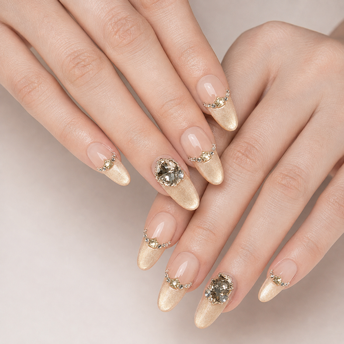 Two overlapping hands wearing Gilded Cadence Long Oval press-on nails with champagne tips and two smoky crystal accents