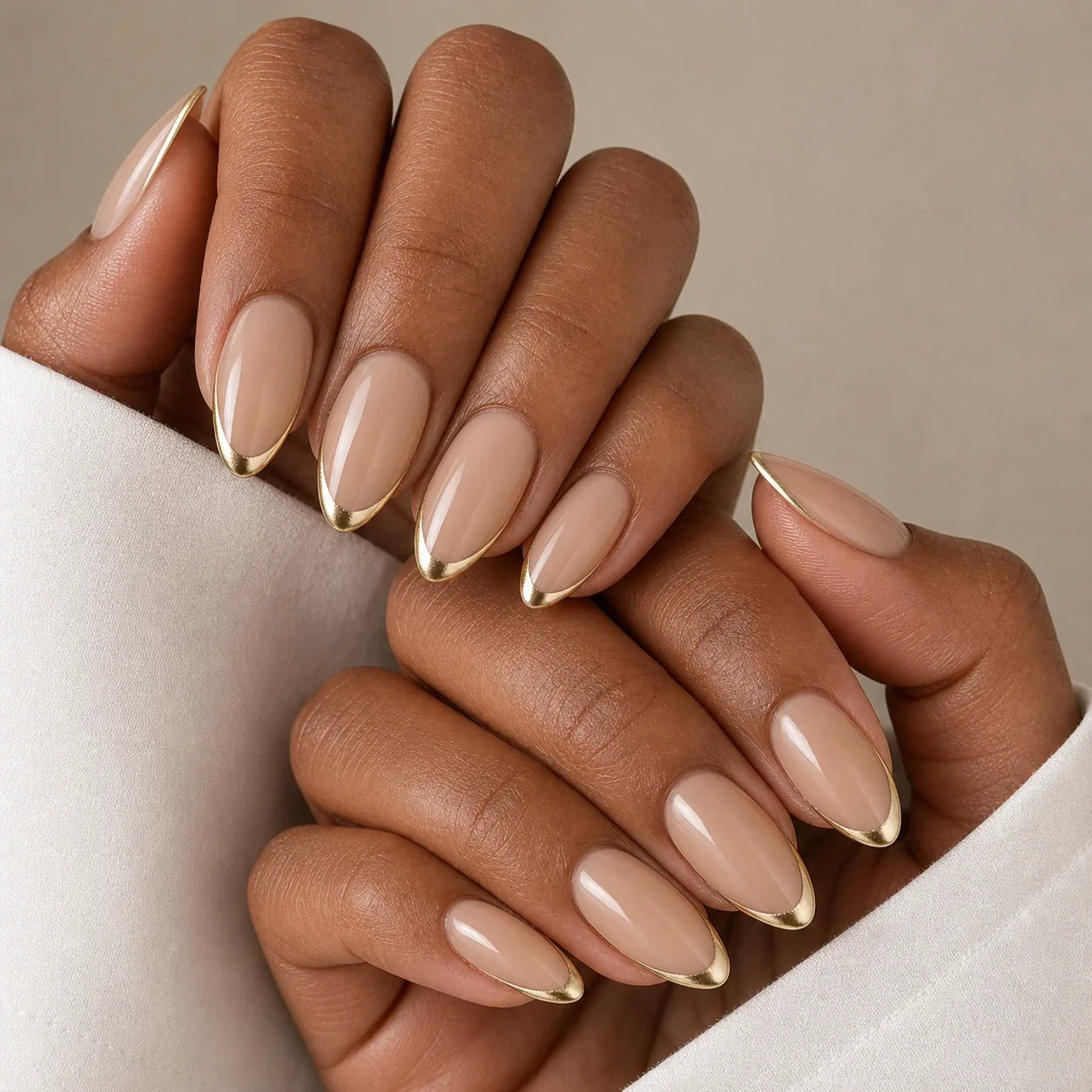 Gilded Whisper nude and gold manicure on two medium-brown hands