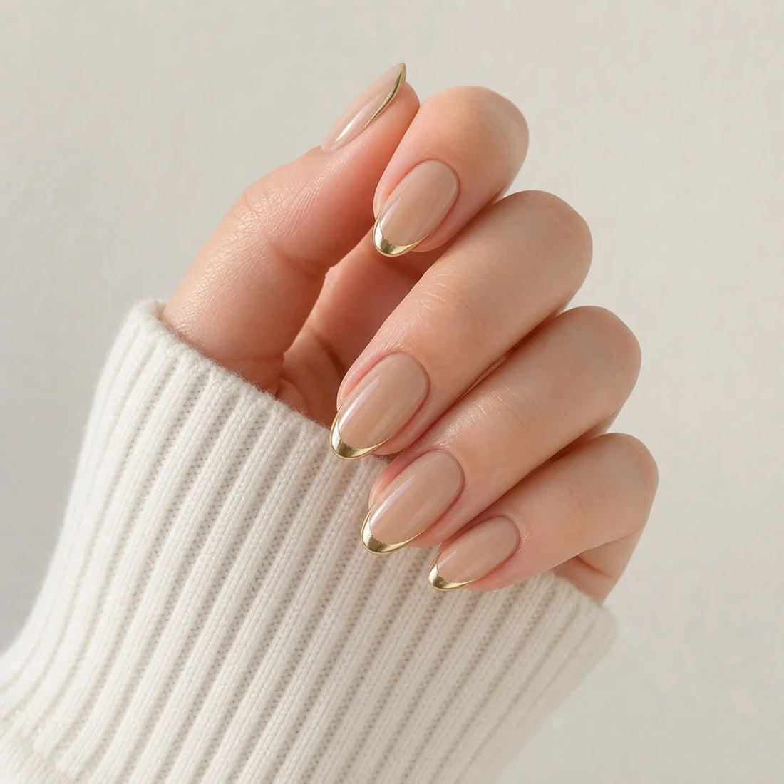 Gilded Whisper gold micro-French press-on manicure on one curled hand