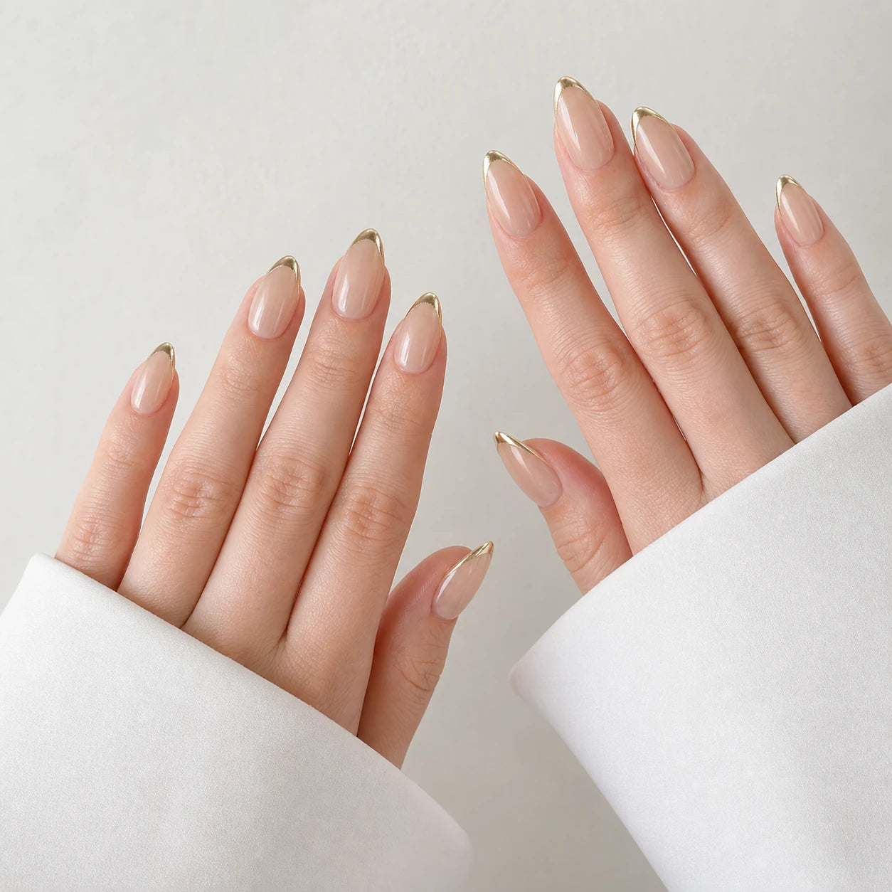 Gilded Whisper medium almond gold micro-French nails on two open light-skinned hands