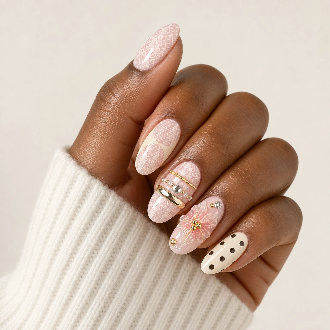 Lace Confetti pink ivory lace polka dot short almond press-on nails on one medium-brown hand