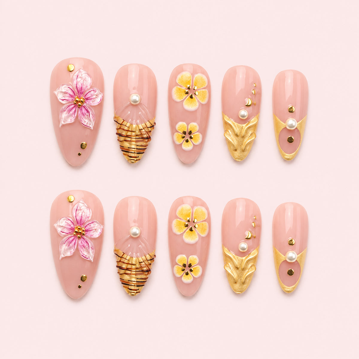 Gilded Hibiscus is a 24-piece handmade medium almond press-on nail set in blush pink, petal pink, yellow and gold, featuring raised flowers, sculptural gold leaves, fan-like gold linework, pearls and studs. It is designed as a reusable multi-size at-home manicure with no selectable size variant, flat lay