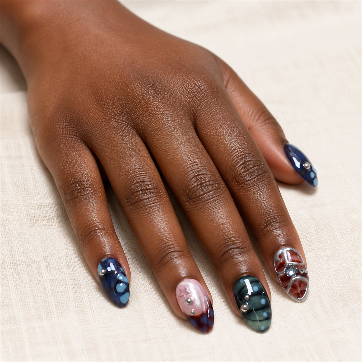 Orbit Patchwork press-on nails shown on dark-skinned one hand