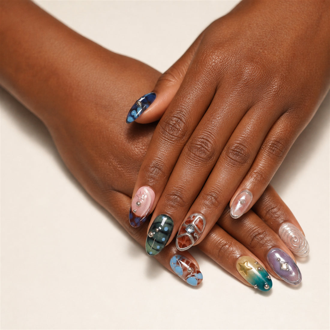 Orbit Patchwork press-on nails shown on dark-skinned two hands