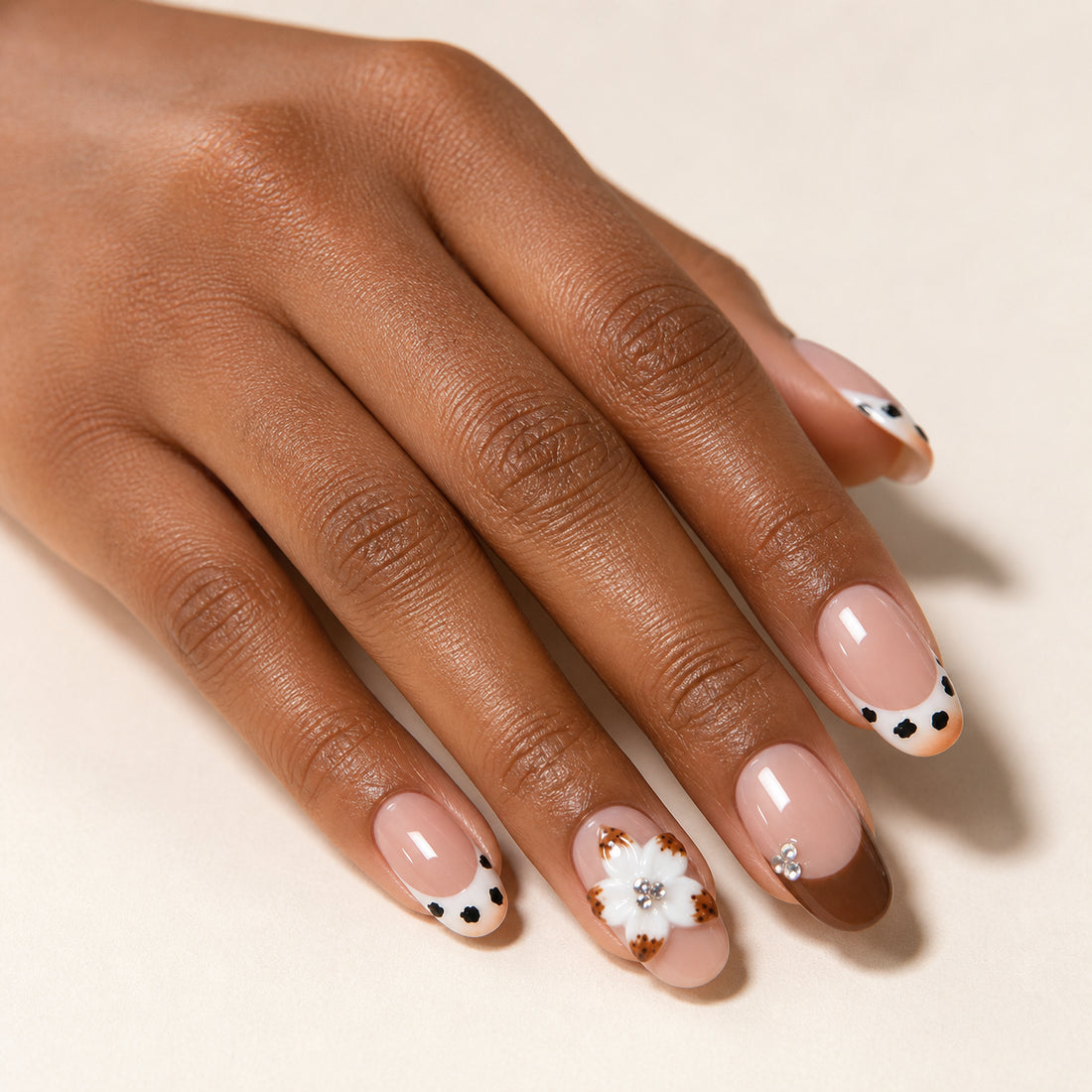 Spotted Magnolia press-on nails shown on dark-skinned one hand