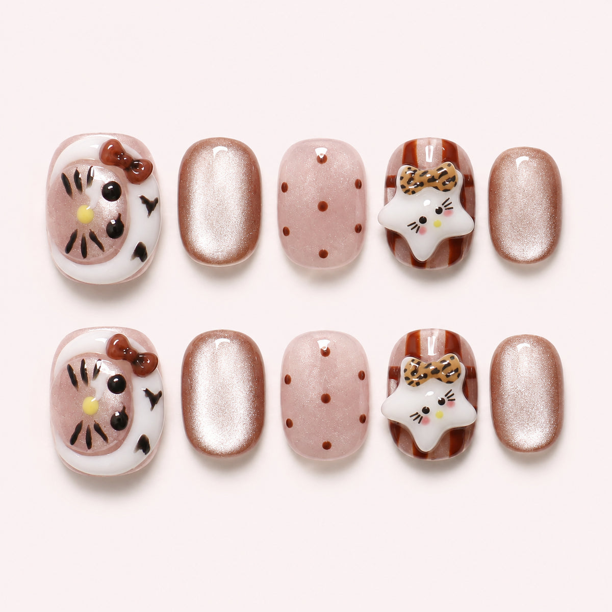 Toffee Kitty press-on nails in caramel, blush and champagne shimmer with 3D cat faces, leopard-print bows and polka dots, flat lay