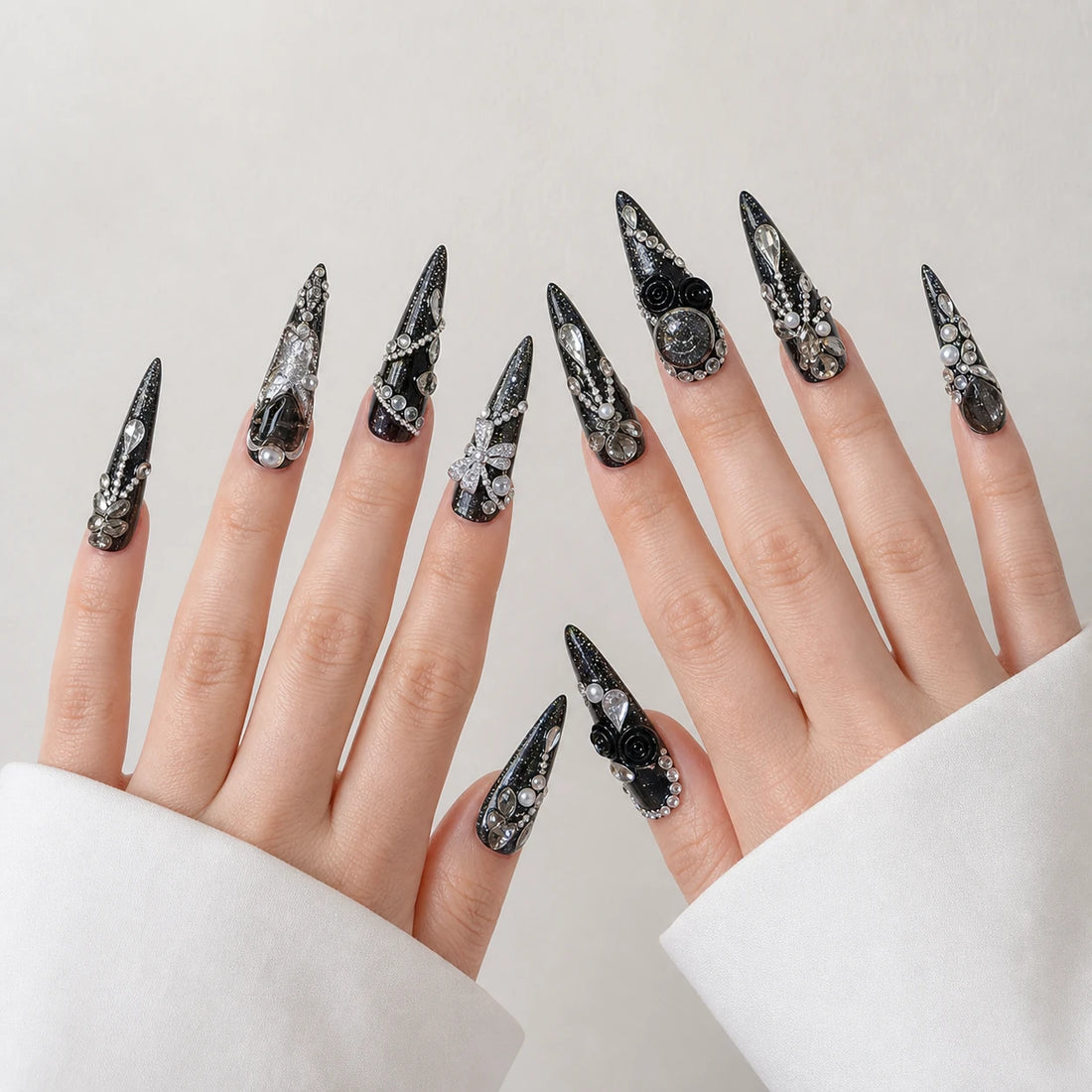 Midnight Heirloom black silver long stiletto nails on two open light-skinned hands