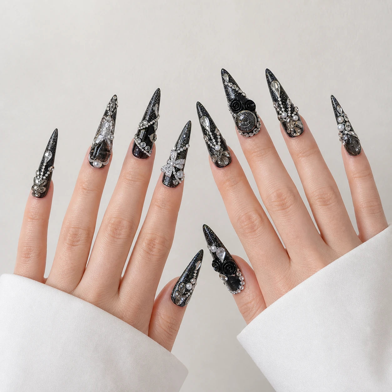 Midnight Heirloom black silver long stiletto nails on two open light-skinned hands
