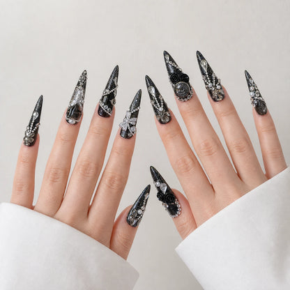 Midnight Heirloom black silver long stiletto nails on two open light-skinned hands