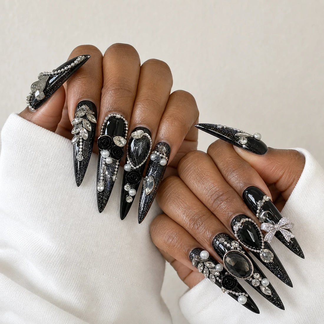 Midnight Heirloom black crystal manicure on two medium-brown hands