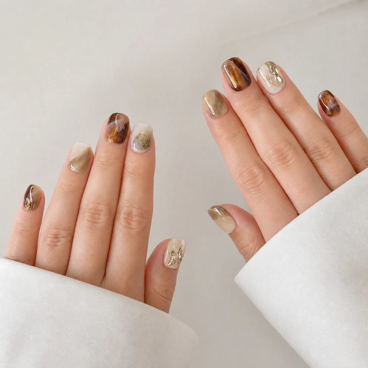 Molten Mocha short squoval press-on nails on two open hands