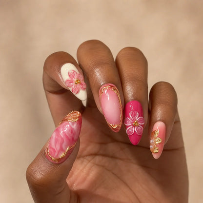 Petal Regalia gold bow manicure on one medium-brown hand