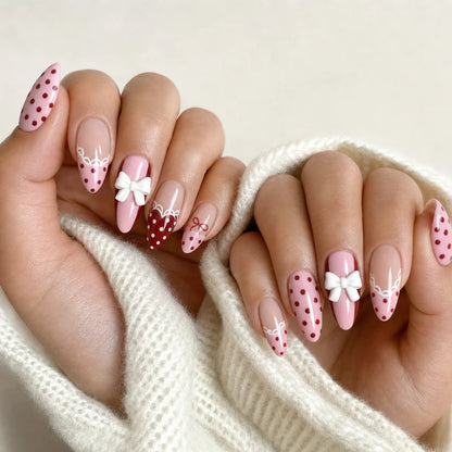 Polka Pirouette pink bow medium almond press-on nails on two softly curled hands, new option