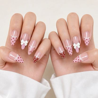 Polka Pirouette pink bow medium almond press-on nails on two open hands, new option