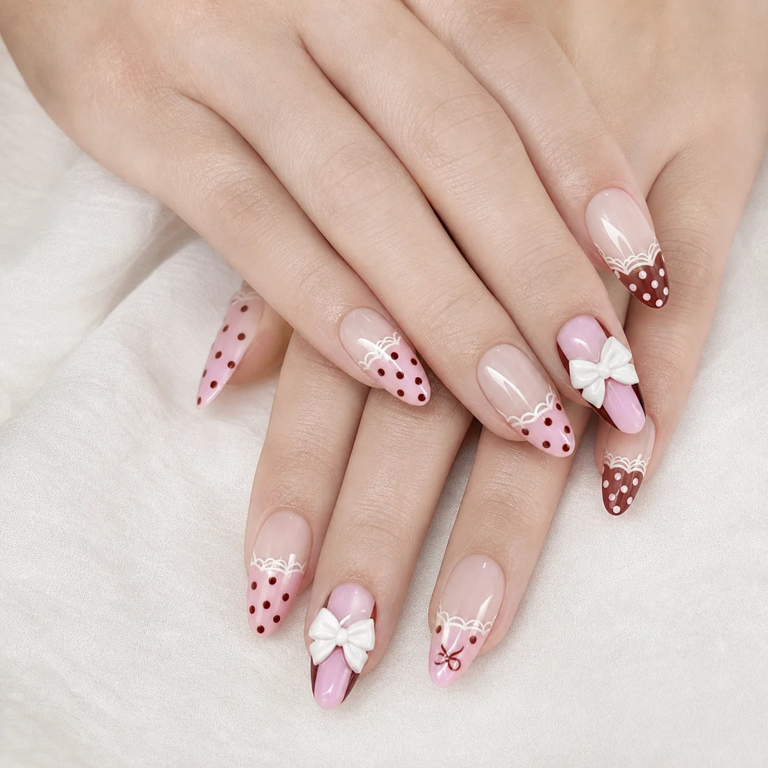 Polka Pirouette pink bow medium almond press-on nails on two gently stacked hands, new option