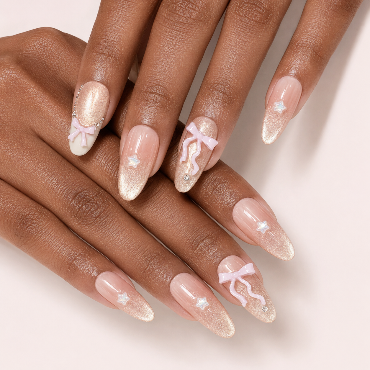 Two softly crossed hands wearing Ribbon Constellation Long Oval press-on nails with bows and stars