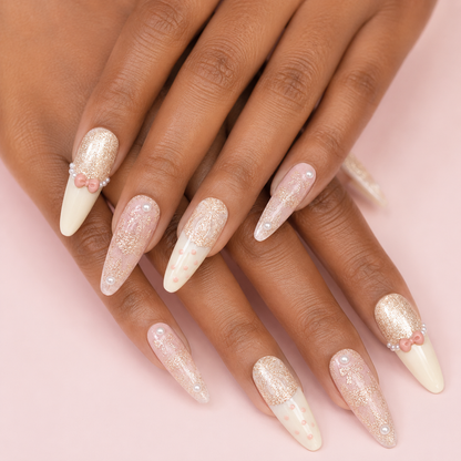 Two crossed hands wearing Ribbon Souffle Long Stiletto press-on nails with champagne shimmer and bows