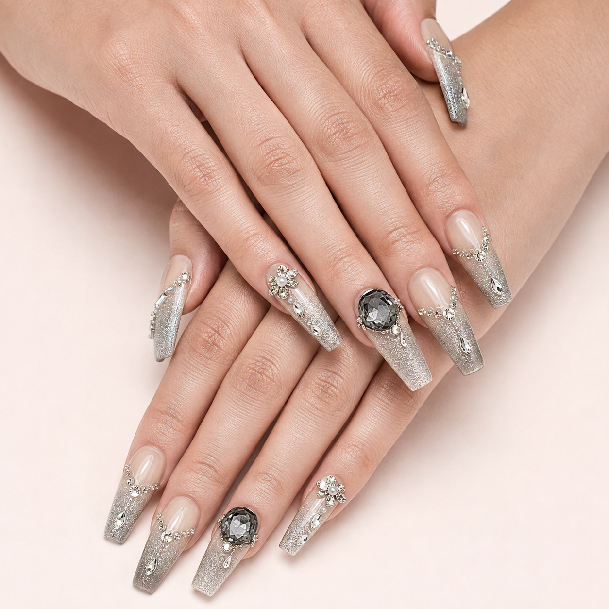 Crossed light-skin hands wearing Smoky Diadem long coffin press-on nails with floral rhinestones and smoky grey gems