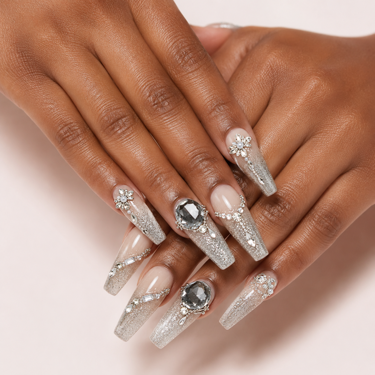 Crossed medium-brown hands wearing Smoky Diadem long coffin press-on nails with floral details and faceted grey gems