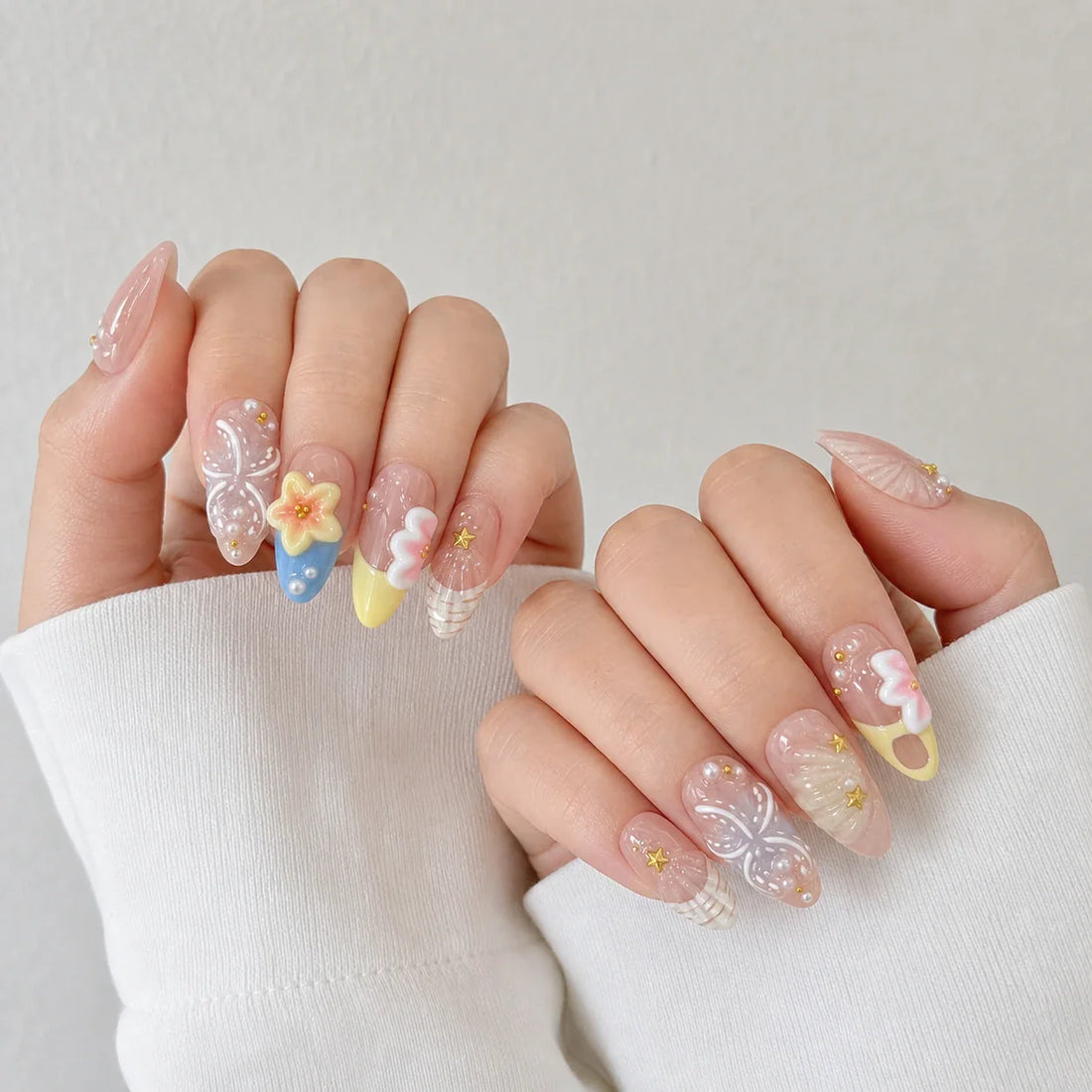 Sunlit Lagoon floral and shell press-on manicure on two softly curled hands