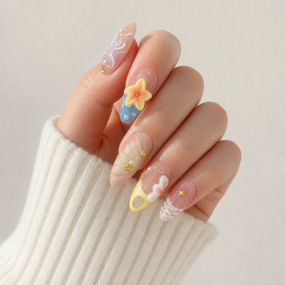 Sunlit Lagoon yellow and blue floral press-on manicure on one softly curled hand