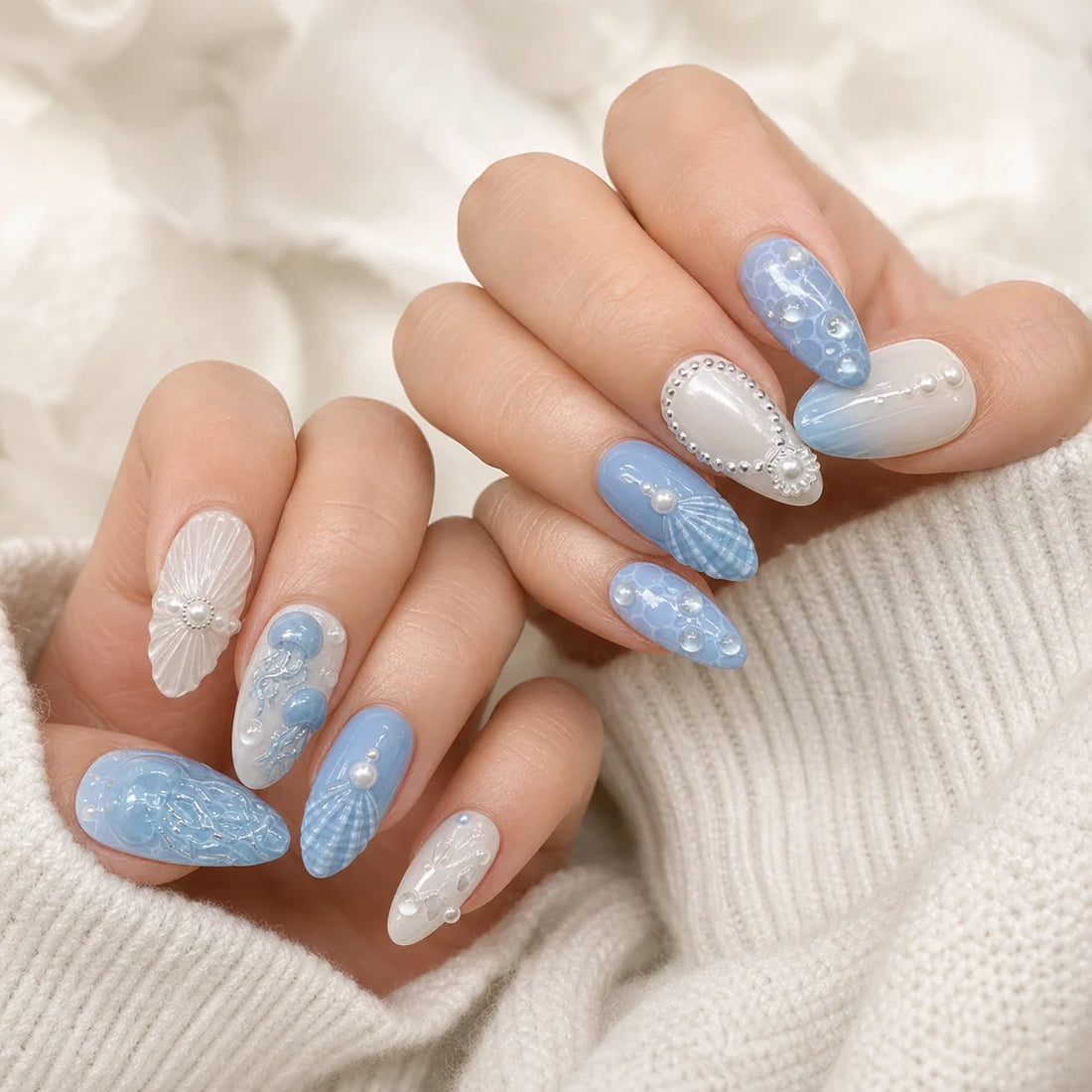 Tidal Cameo blue and white ocean press-on manicure on two softly curled hands