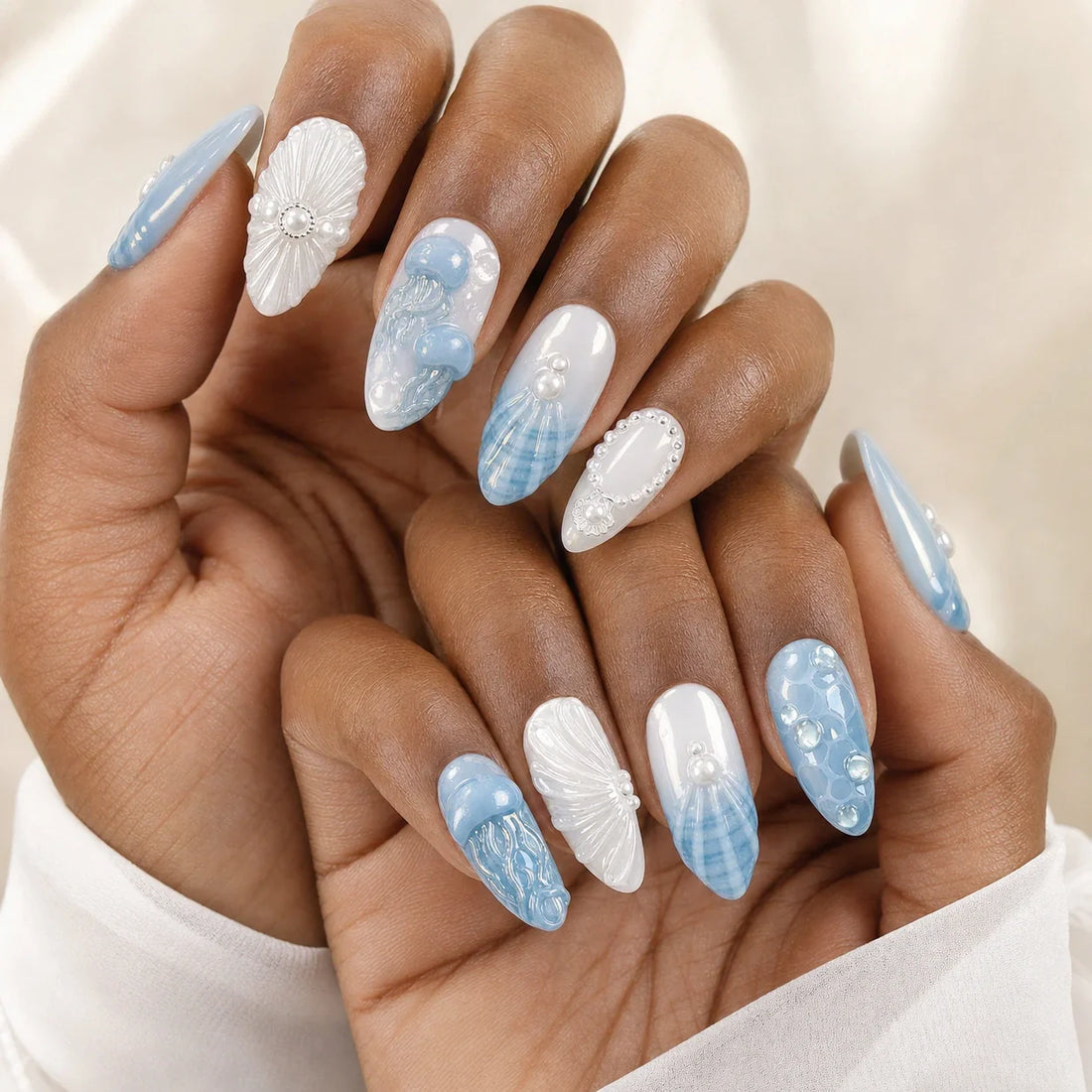 Tidal Cameo pearlescent ocean press-on nails on two medium-brown hands