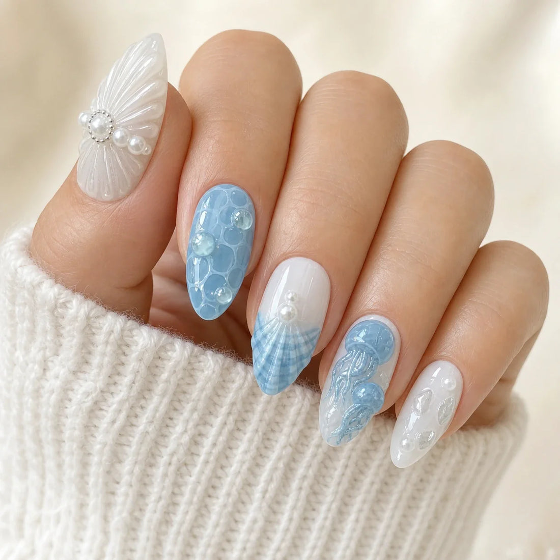 Tidal Cameo blue and white shell manicure on one softly curled hand